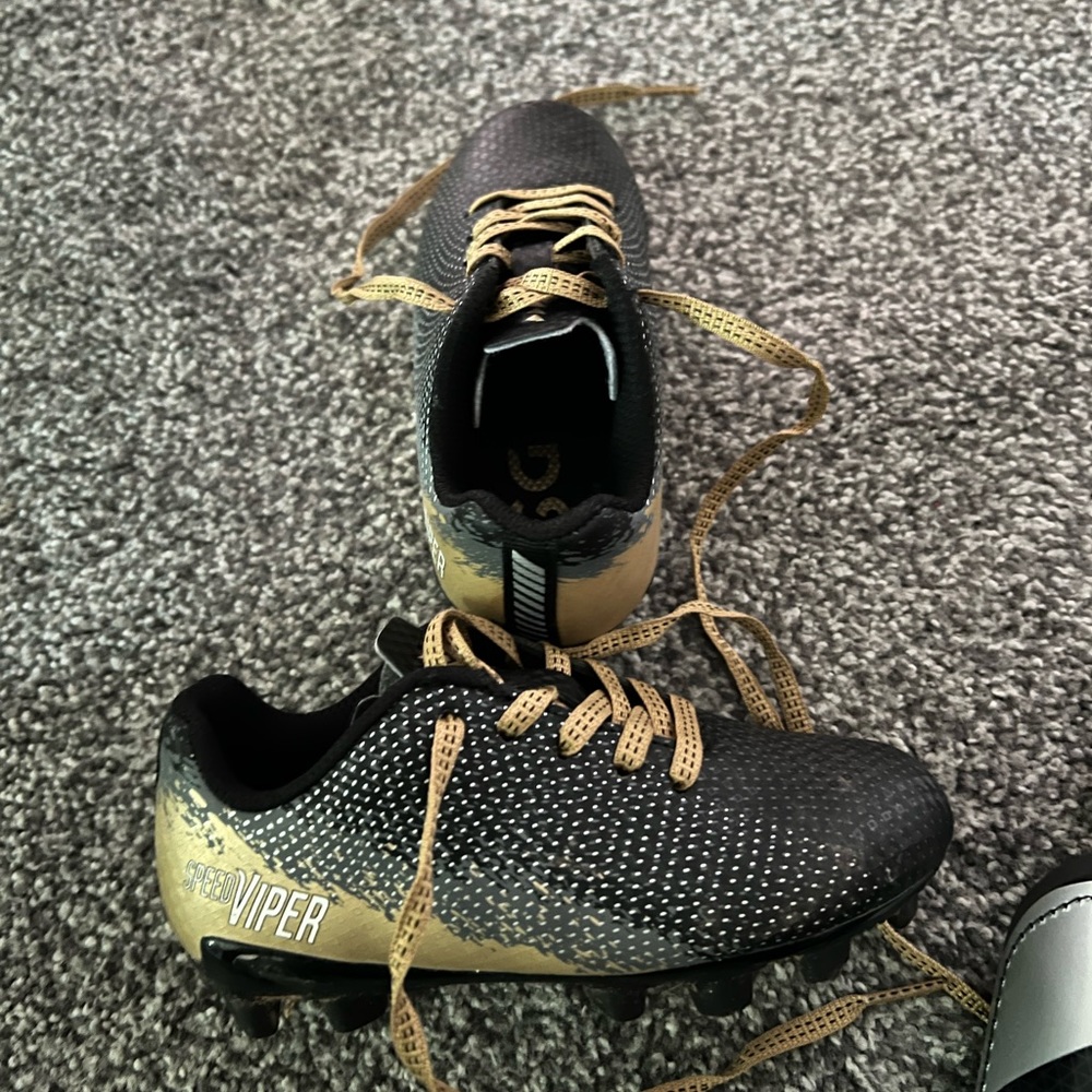Size 9 soccer cleats and shin guards. Toddler size. Black and gold color.